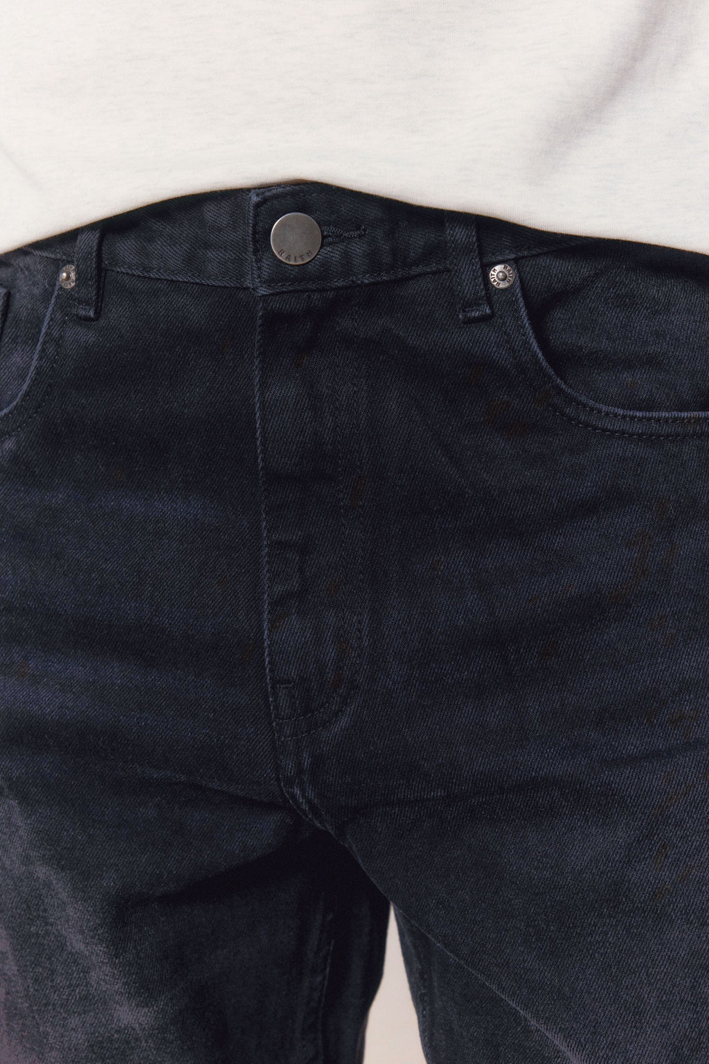 Close-up of Mason Relaxed Fit Jeans in black wash 100% cotton denim, showing button fly and front pockets.