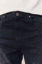 Close-up of Mason Relaxed Fit Jeans in black wash 100% cotton denim, showing button fly and front pockets.