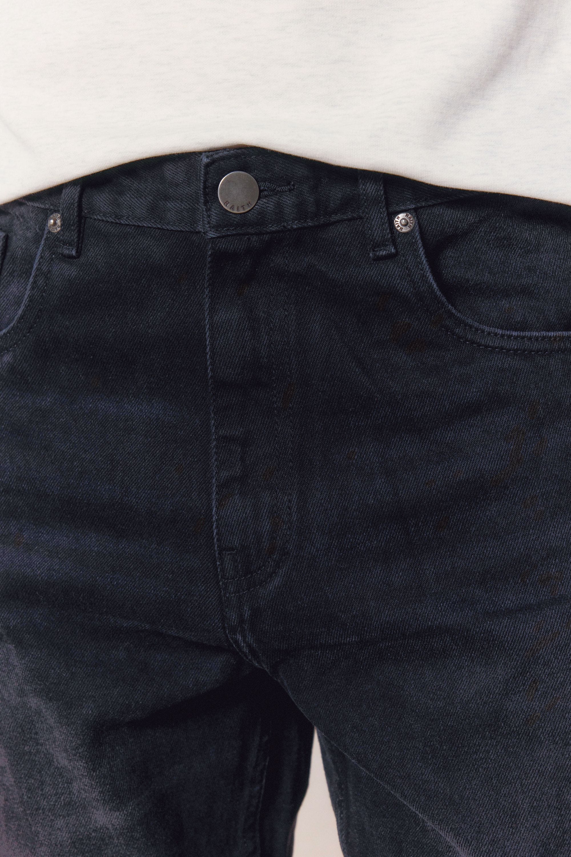 Close-up of Mason Relaxed Fit Jeans in black wash 100% cotton denim, showing button fly and front pockets.