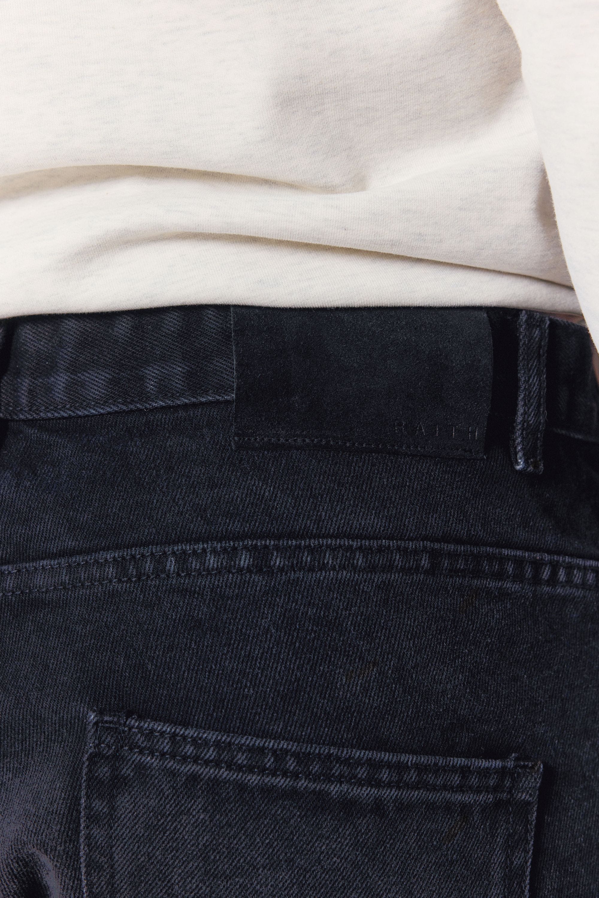 Close-up of Mason Relaxed Fit Jeans in black wash, showing the dyed-to-match leather back patch.