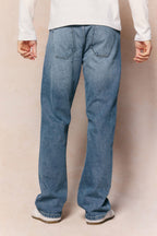 Mason Relaxed Fit Jeans in midwash indigo 100% cotton denim, shown from behind with tan leather patch.