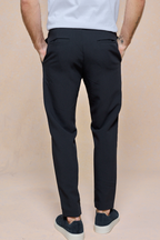 Rear view of a man wearing black Mateo tapered trousers with an elasticated drawcord waistband.