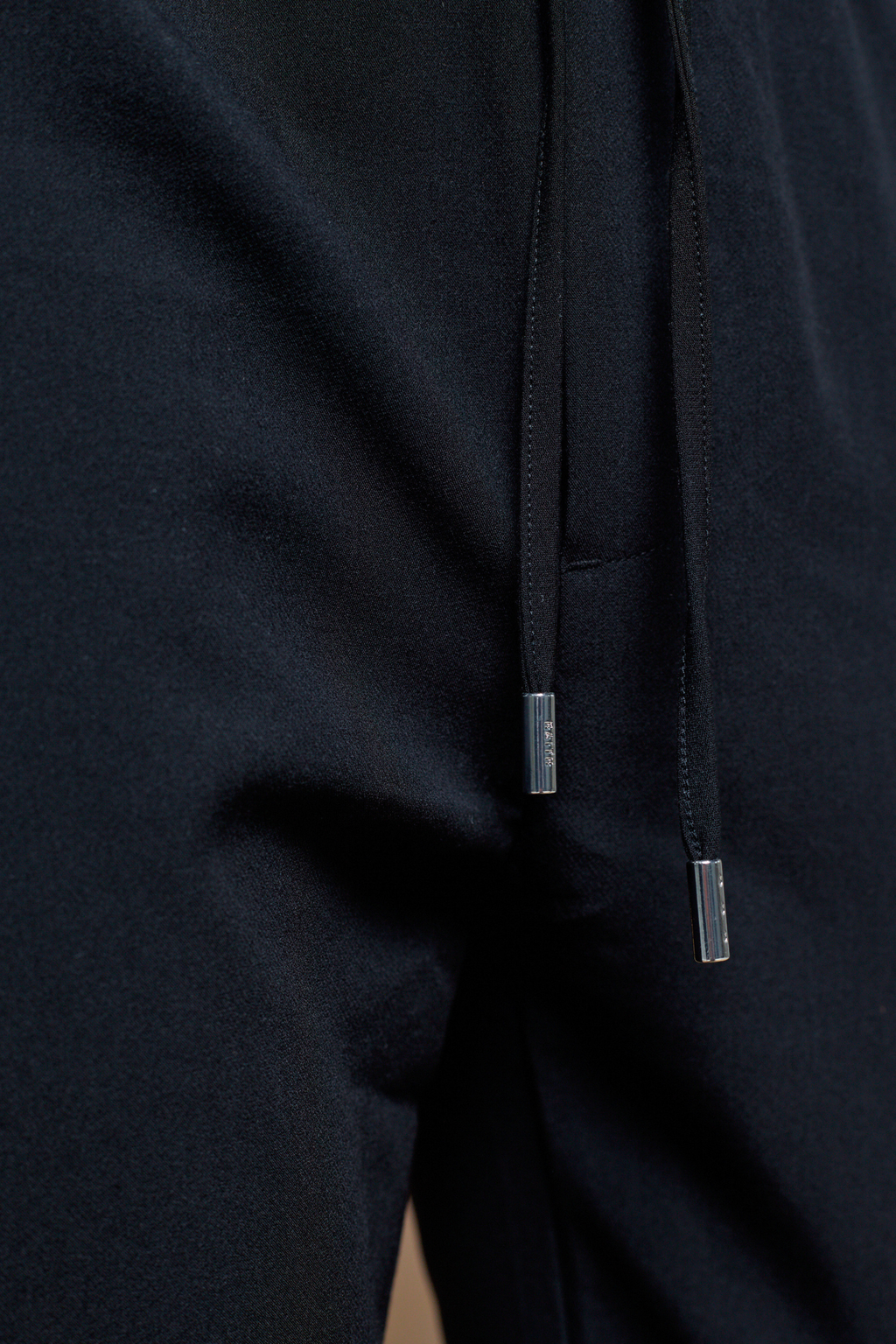 Close-up of black Mateo Tapered Trouser with elasticated drawcord waistband and silver metal tips.