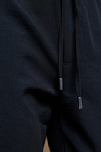 Close-up of black Mateo Tapered Trouser with elasticated drawcord waistband and silver metal tips.