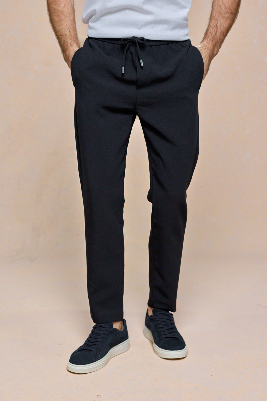 Black Mateo Tapered Trouser with elasticated drawcord waistband, worn by a person with hands in pockets.
