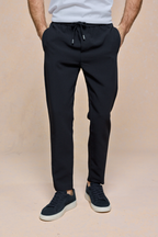 Black Mateo Tapered Trouser with elasticated drawcord waistband, worn by a person with hands in pockets.