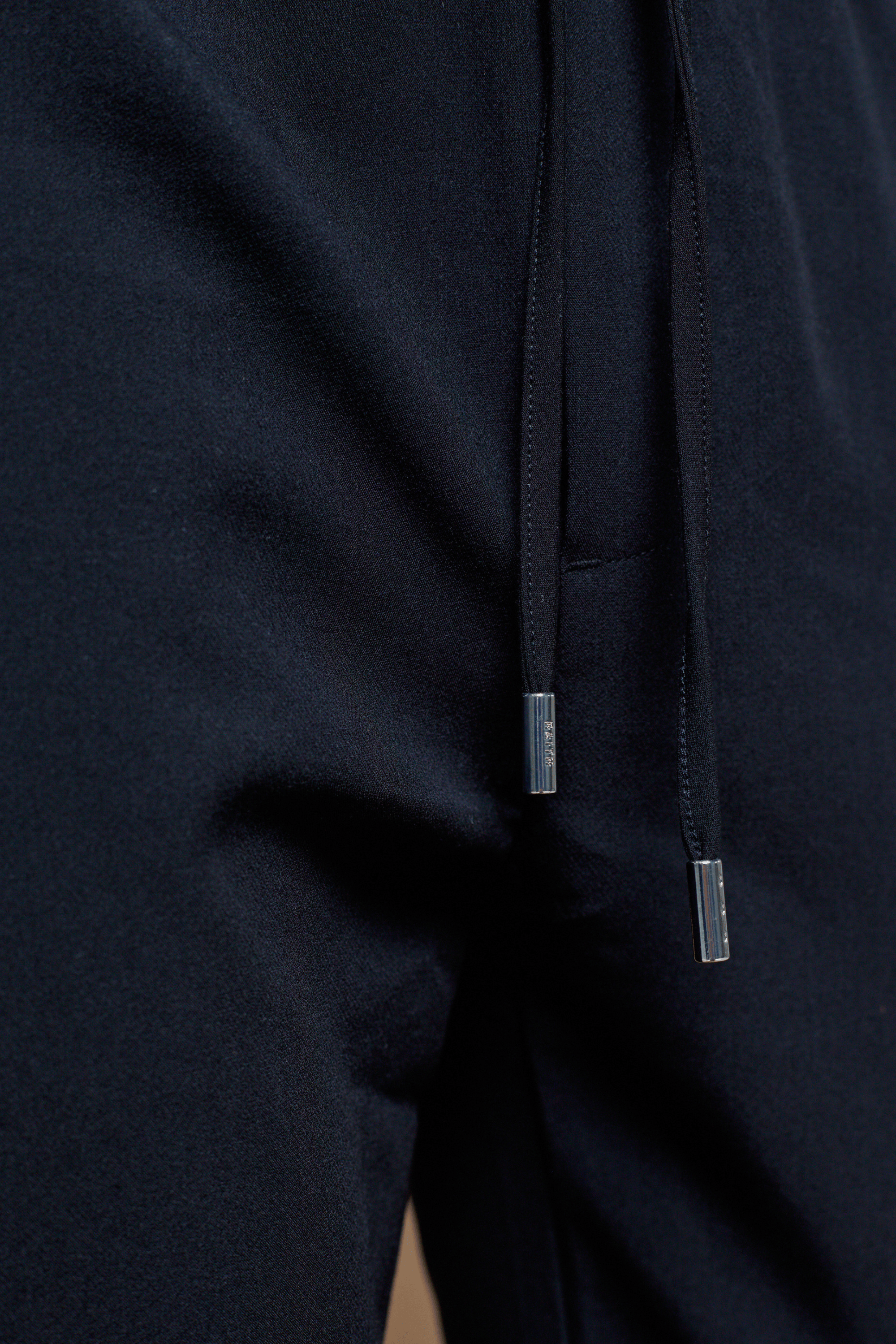Close-up of dark navy Mateo Tapered Trouser with elasticated drawcord waistband and silver aglets.