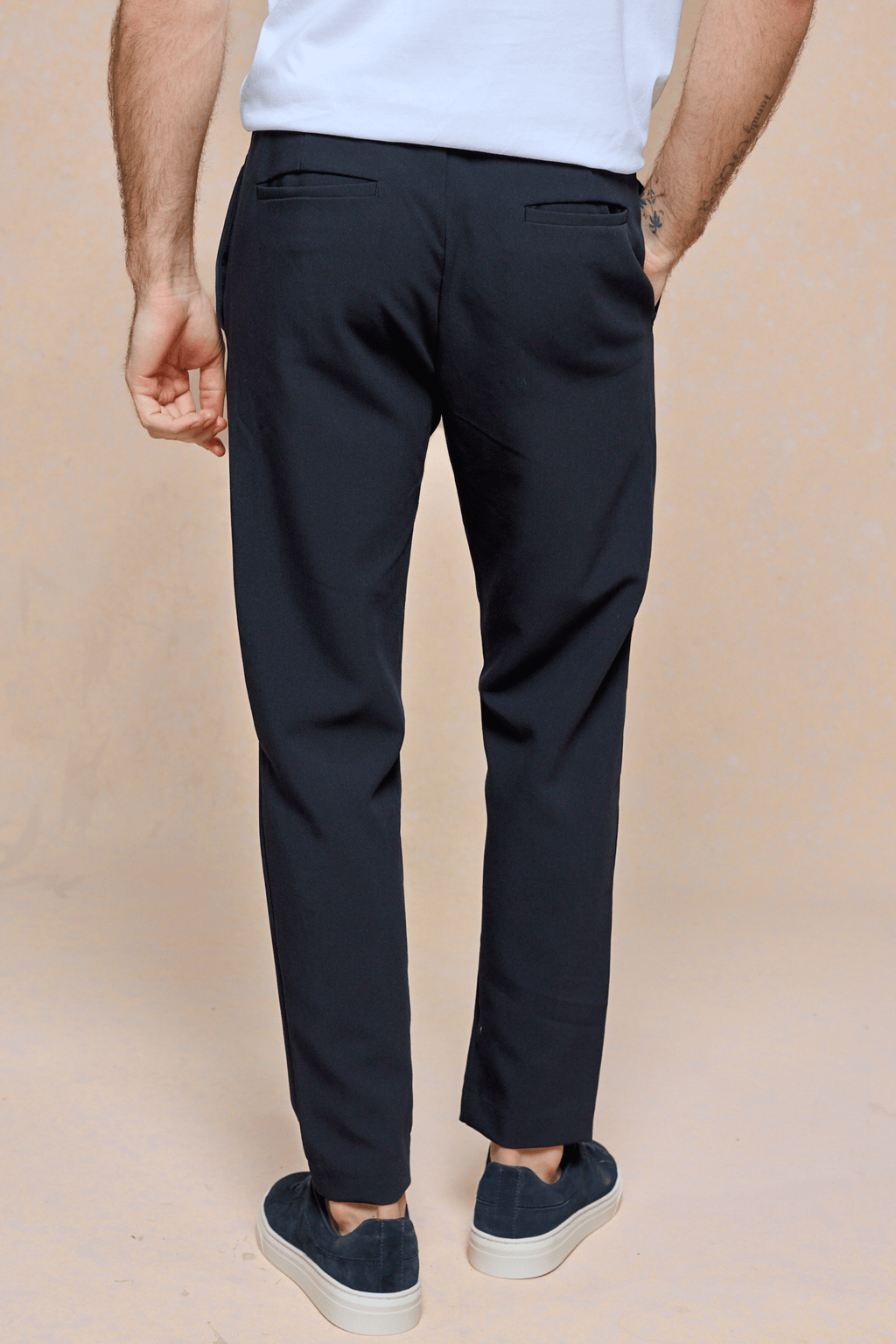 Man wearing dark navy Mateo Tapered Trousers with an elasticated drawcord waistband and back pockets.