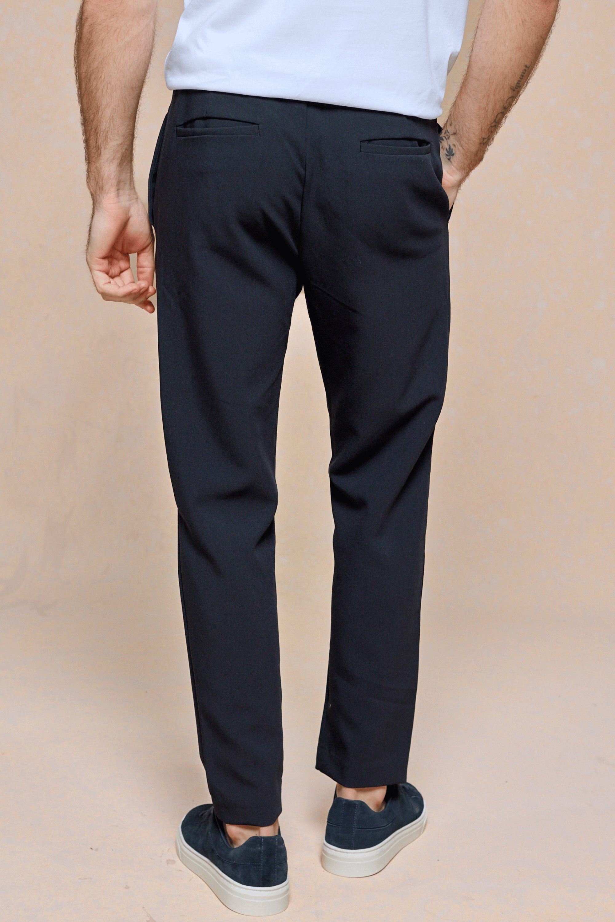 Man wearing dark navy Mateo Tapered Trousers with an elasticated drawcord waistband and back pockets.