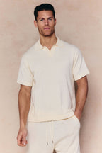 Man wearing an ecru Miguel Boucle Polo Shirt with an open collar and matching shorts.