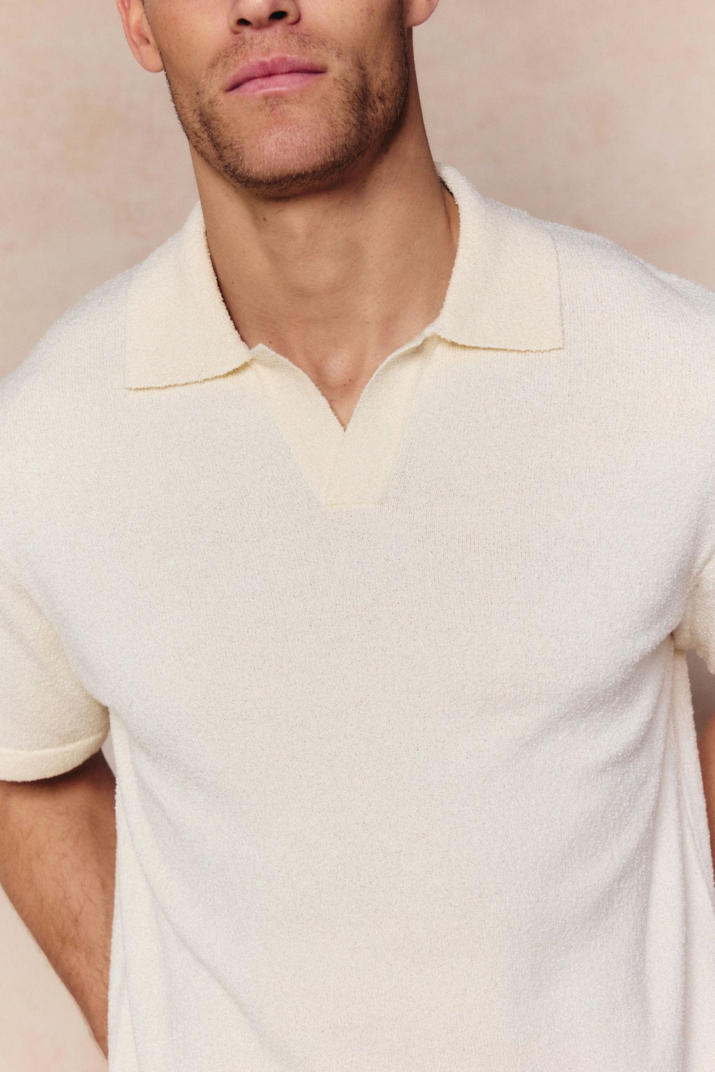 Man wearing an ecru Miguel Boucle Polo Shirt with a textured fabric and open collar.