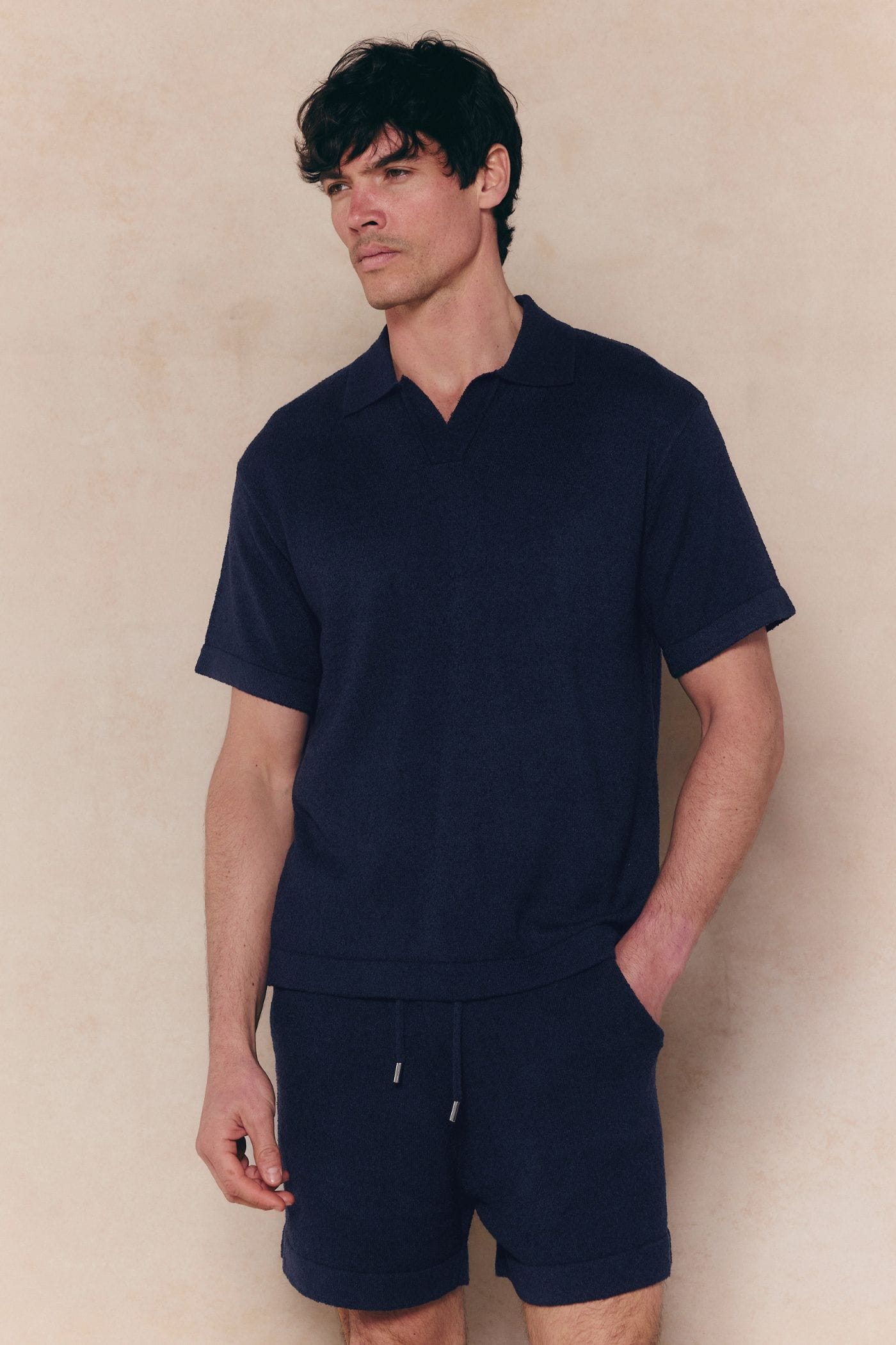 Man in a relaxed fit navy Miguel Boucle Polo Shirt with an open collar and matching shorts.