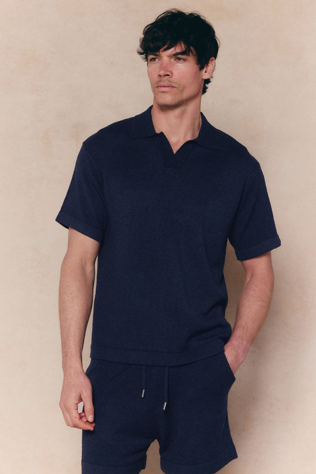 Man wearing a navy Miguel Boucle Polo Shirt with an open collar and matching shorts.