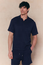 Man wearing a navy Miguel Boucle Polo Shirt with an open collar and matching shorts.