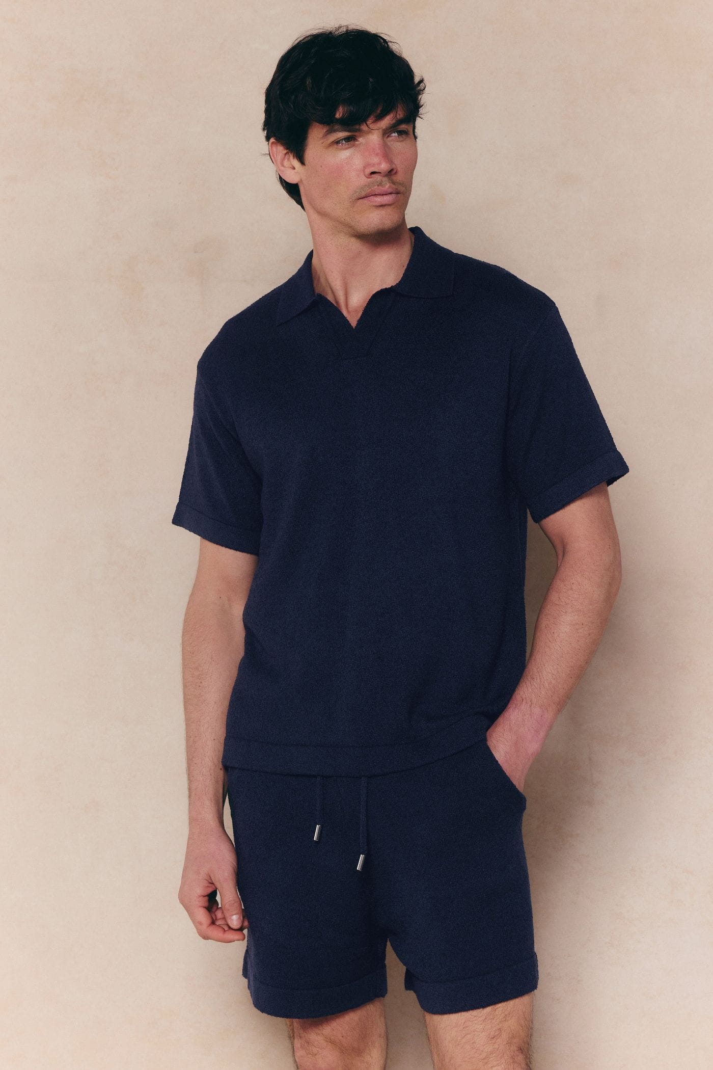 Man wearing a navy Miguel Boucle Polo Shirt with an open collar and matching navy boucle shorts.
