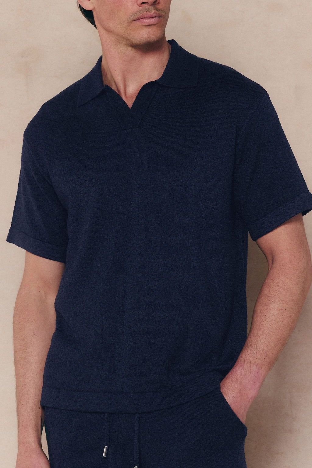 Man wearing a navy Miguel Boucle Polo Shirt with an open collar and textured fabric, paired with matching shorts.