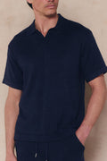 Man wearing a navy Miguel Boucle Polo Shirt with an open collar and textured fabric, paired with matching shorts.