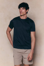 Man wearing a dark blue t-shirt and beige Milo Cargo Tech Shorts with patch side pockets.