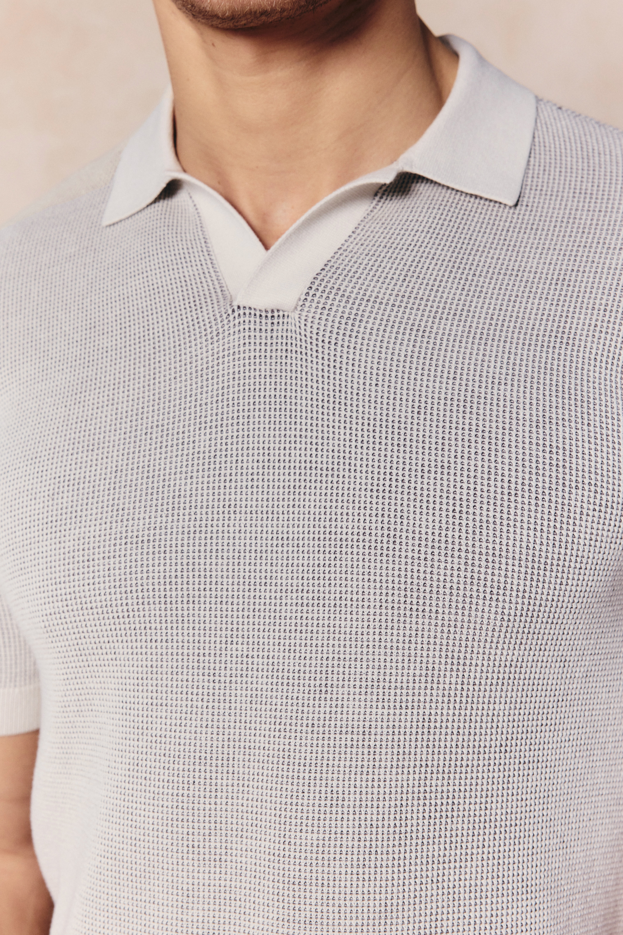 Neutral two-tone double knit cotton polo with an open collar and ribbed trims.