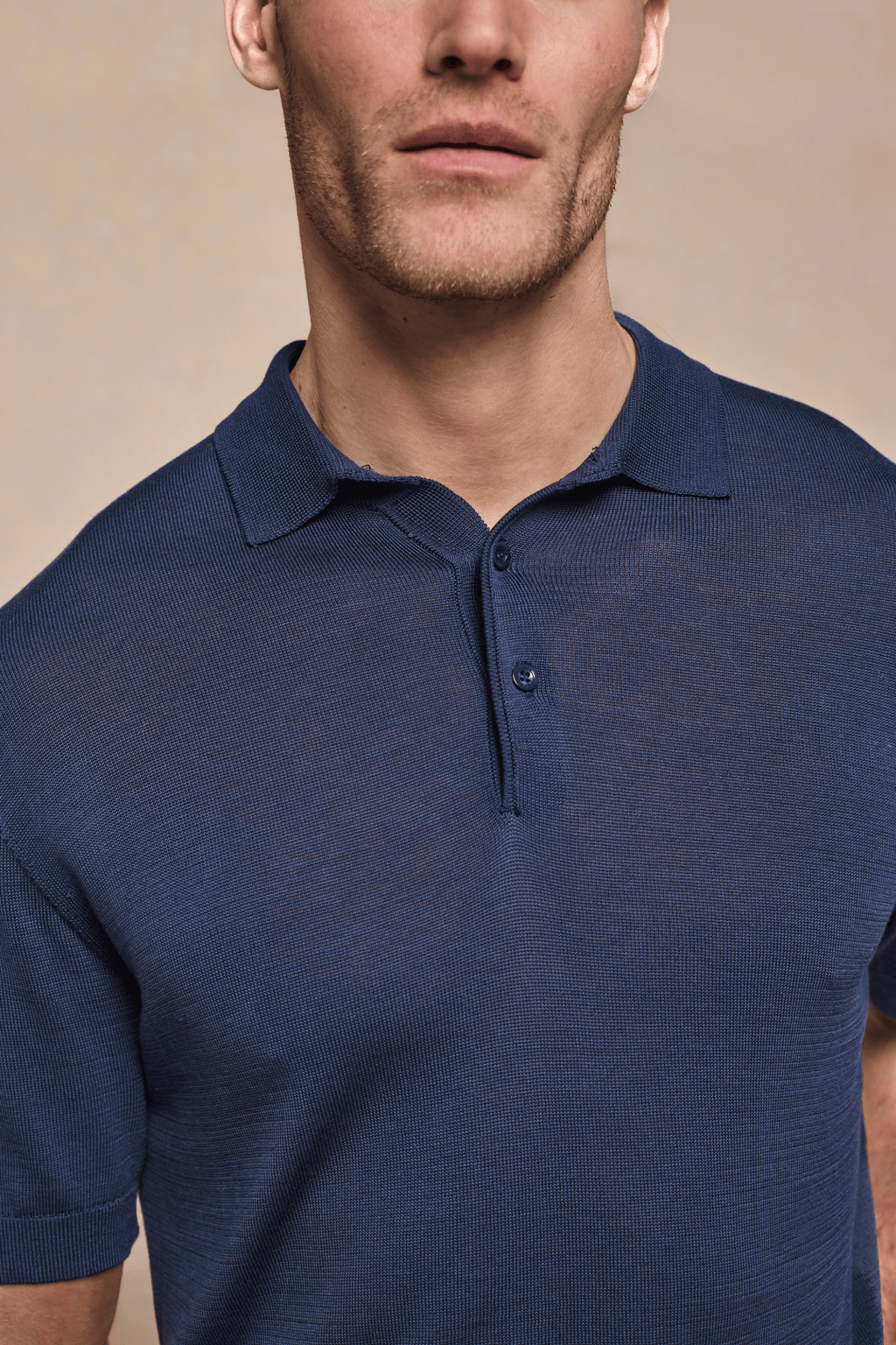 Man wearing a navy Pablo Half Placket Short Sleeve Knitted Polo with ribbed sleeves and branded buttons.
