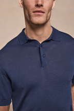 Man wearing a navy Pablo Half Placket Short Sleeve Knitted Polo with ribbed sleeves and branded buttons.