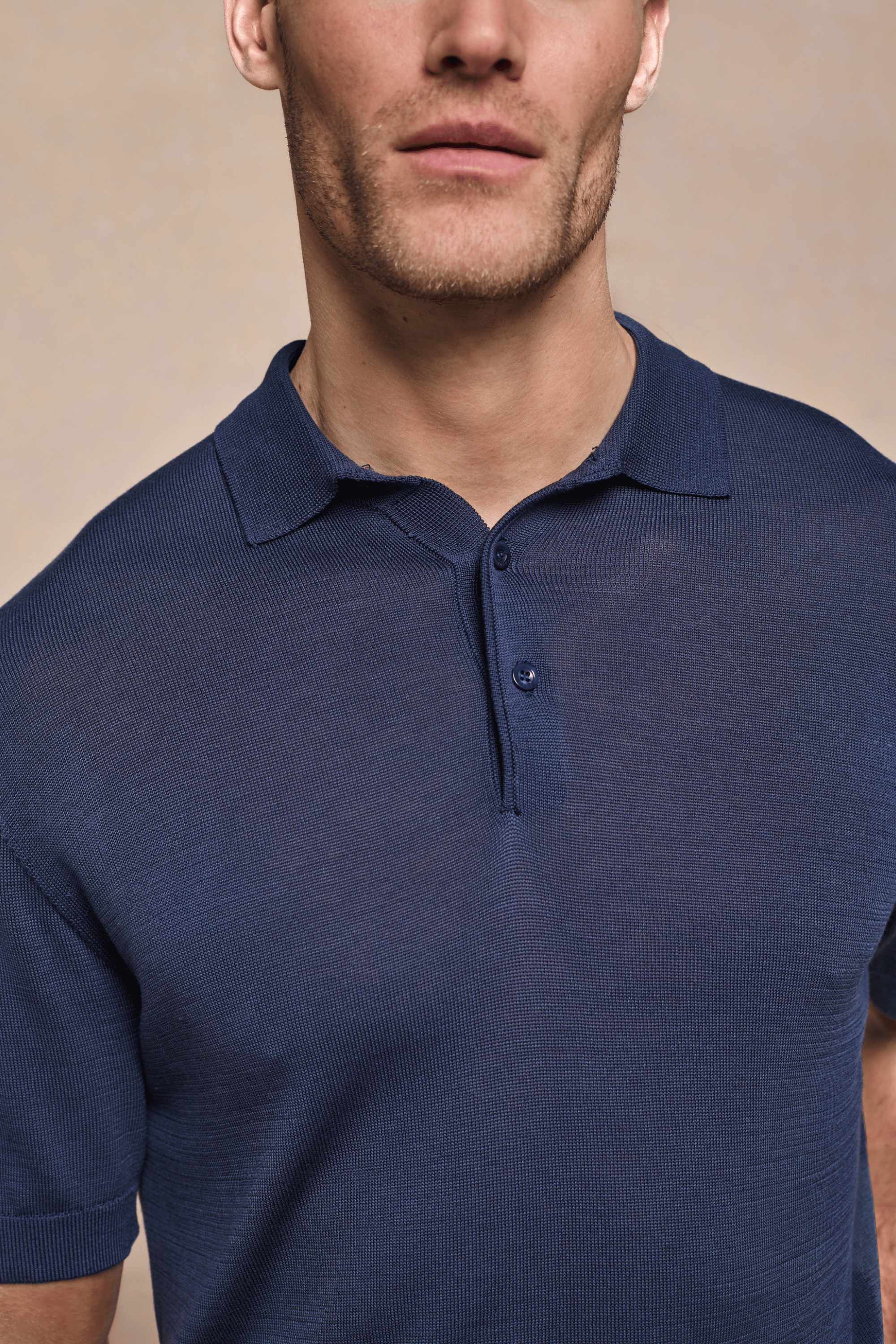 Man wearing a navy Pablo Half Placket Short Sleeve Knitted Polo with ribbed sleeves and branded buttons.