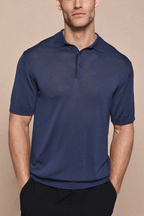 Man wearing a navy knitted short sleeve polo with a half placket and ribbed details.