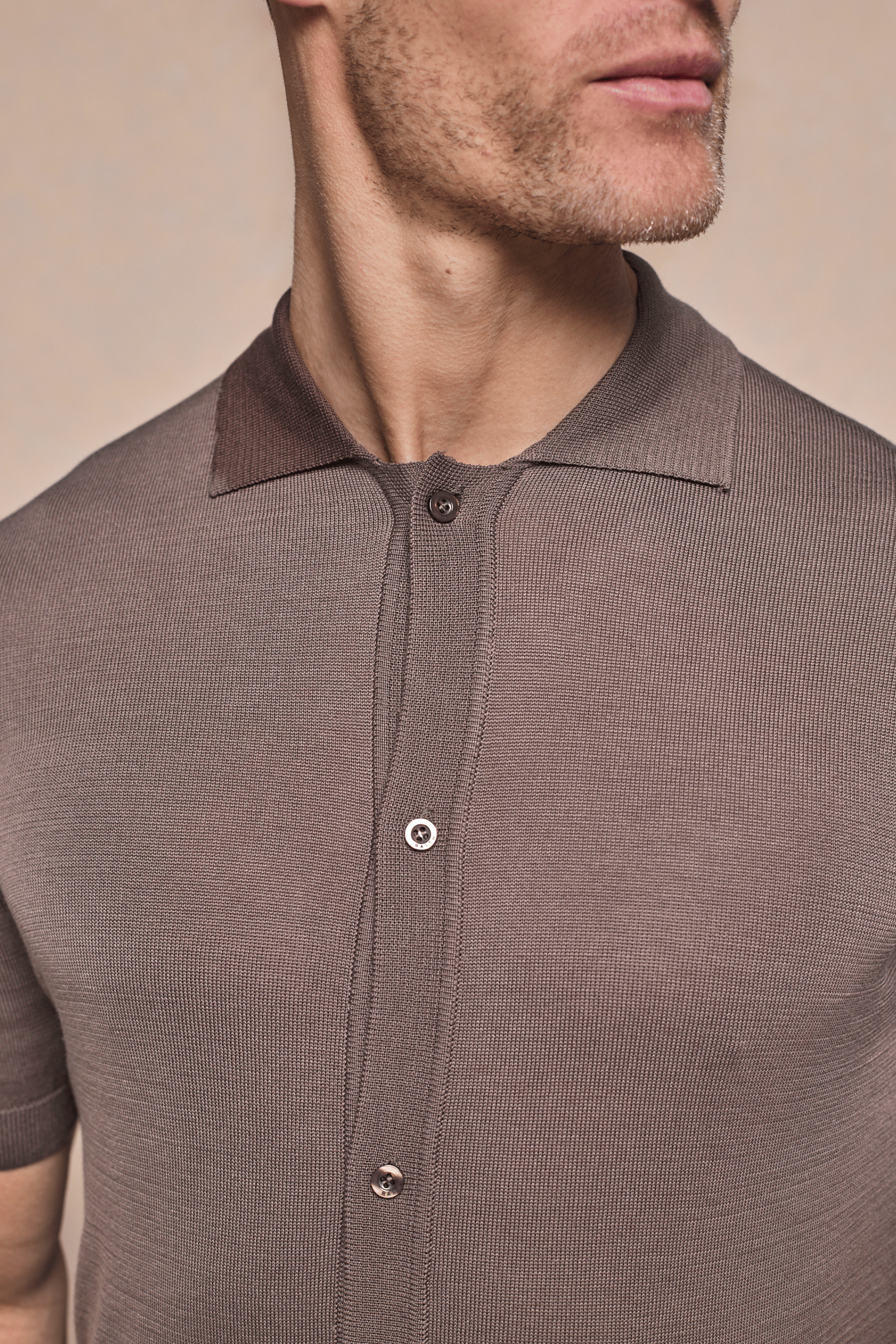 Close-up of a man wearing a brown Pedro knitted shirt with a button-through front and ribbed collar.
