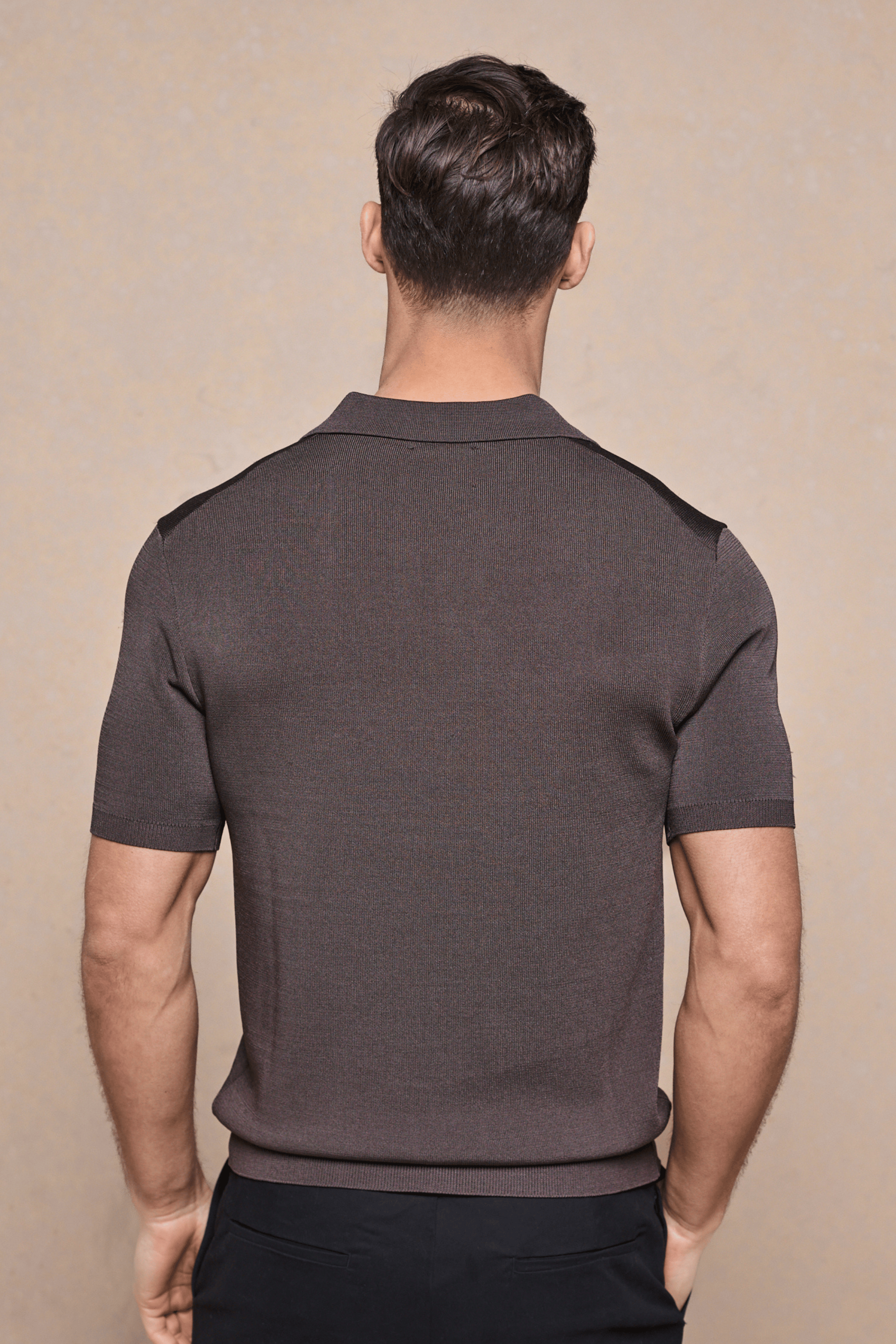 Back view of a man wearing a brown Privida Open Collar Polo, showcasing its ribbed texture and short sleeves.