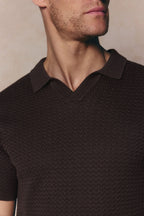Close-up of a man wearing a brown Rapha Cotton Knit Polo with an open collar and textured finish.