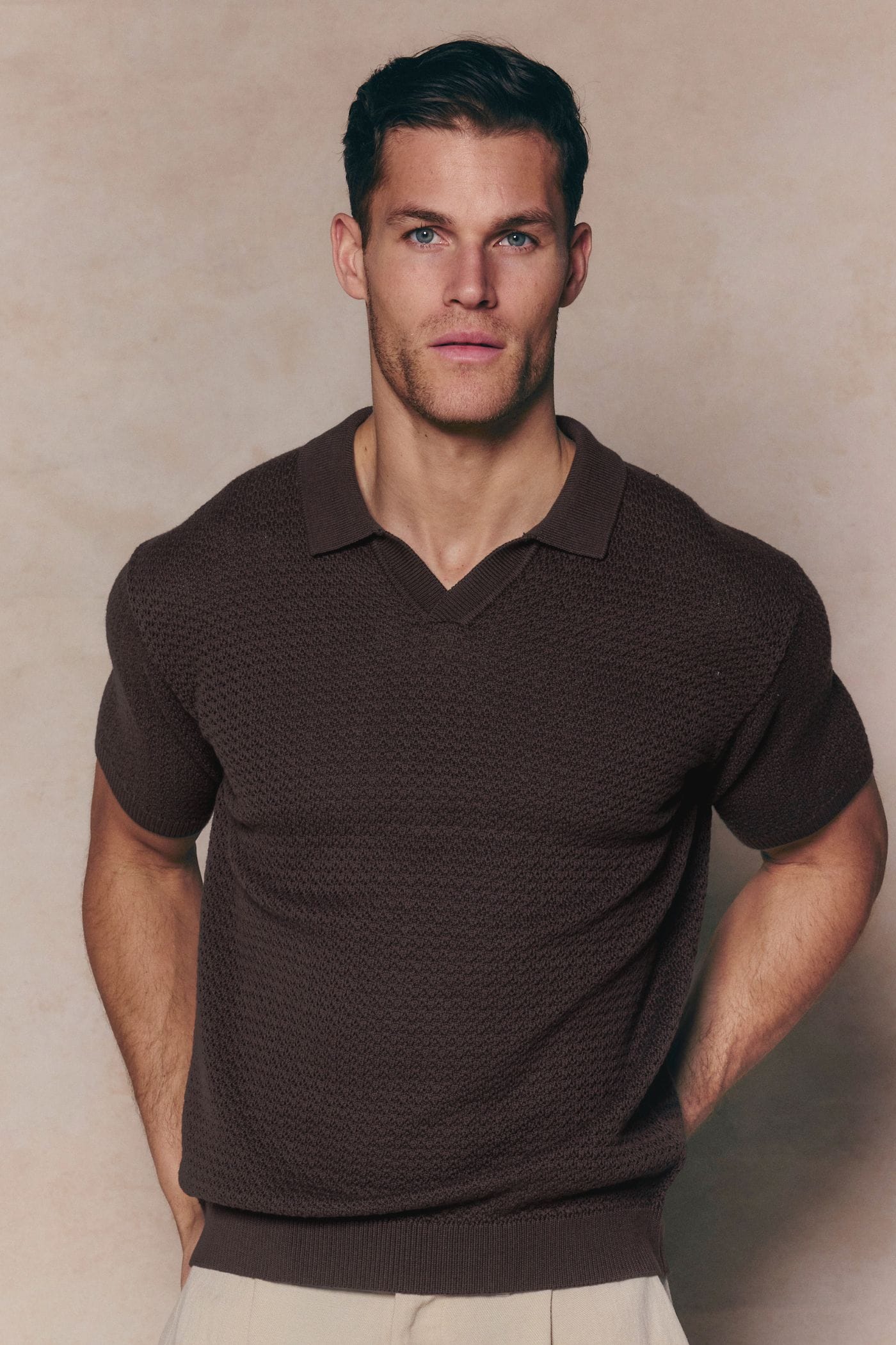 Man wearing a brown Rapha Cotton Knit Polo with an open collar and textured finish.