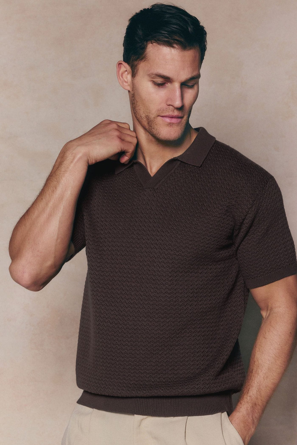 Man wearing a brown Rapha Cotton Knit Polo with an open collar and ribbed hems.