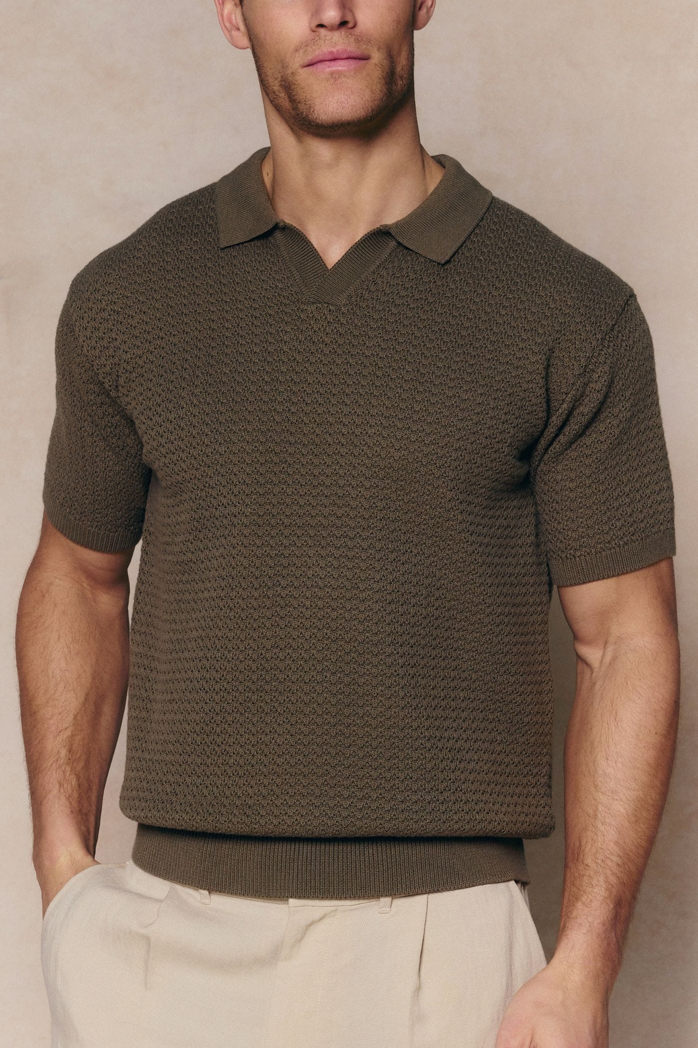 Man wearing a dark olive Rapha Cotton Knit Polo with an open collar and textured finish.
