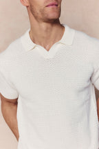Man wearing an ecru Rapha Cotton Knit Polo with an open collar and textured finish.