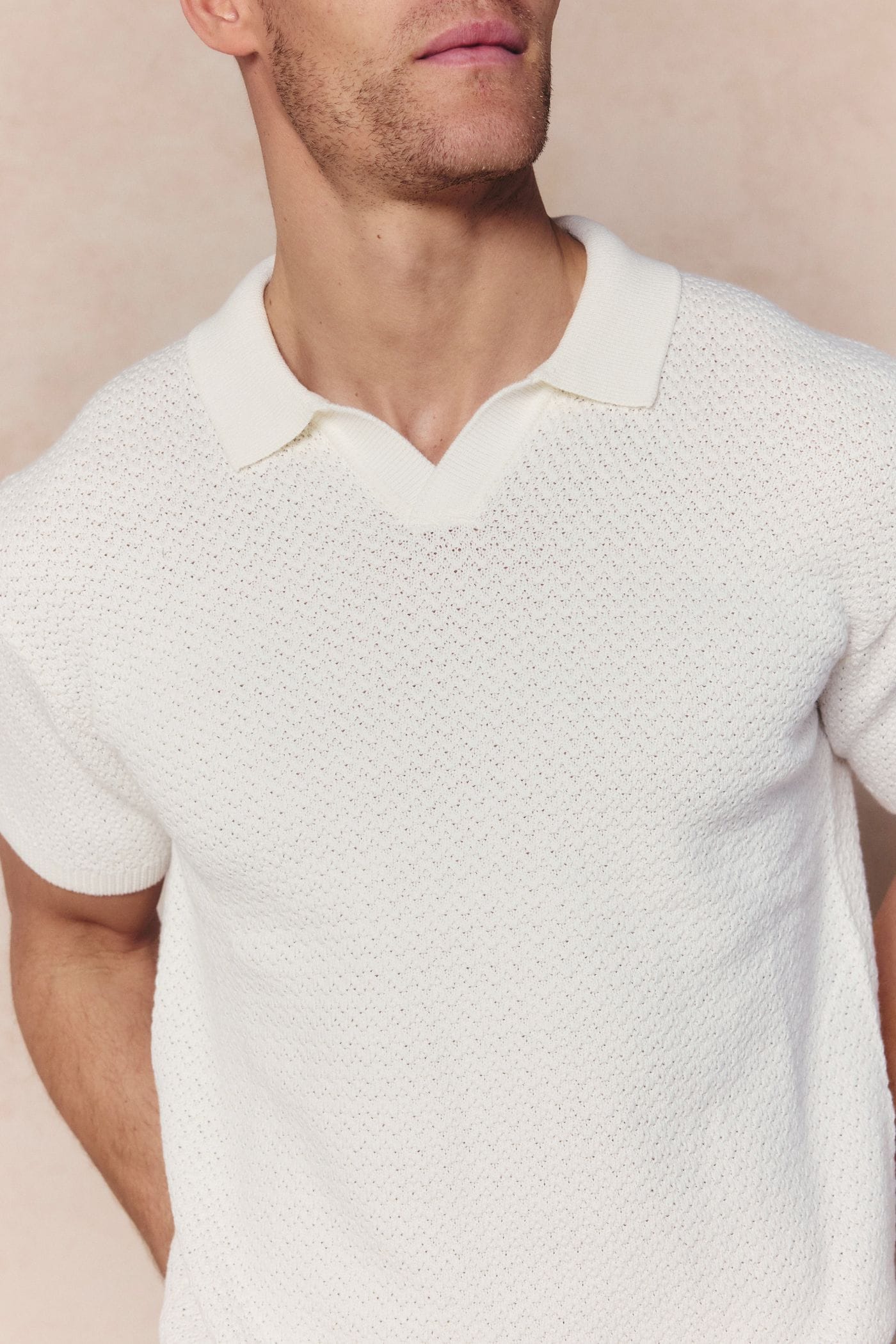 Man wearing an ecru Rapha Cotton Knit Polo with an open collar and textured finish.