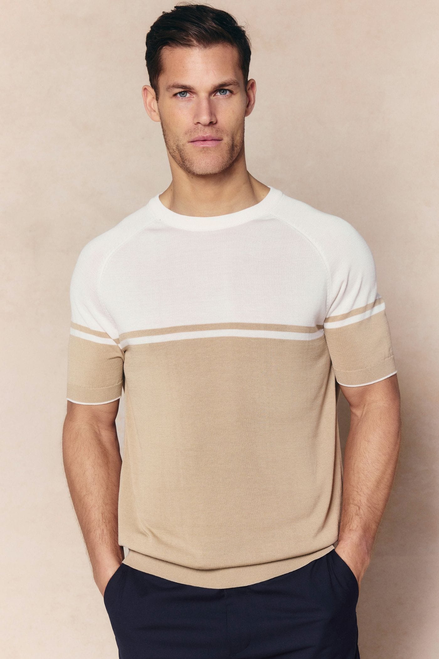 Man in a tailored Riera colour block knit crew neck t-shirt in beige/ecru with ribbed trims.