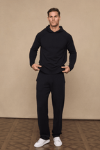 Man wearing a black Rowan Knitted Trouser and matching hoodie, posing with hands on the waistband.