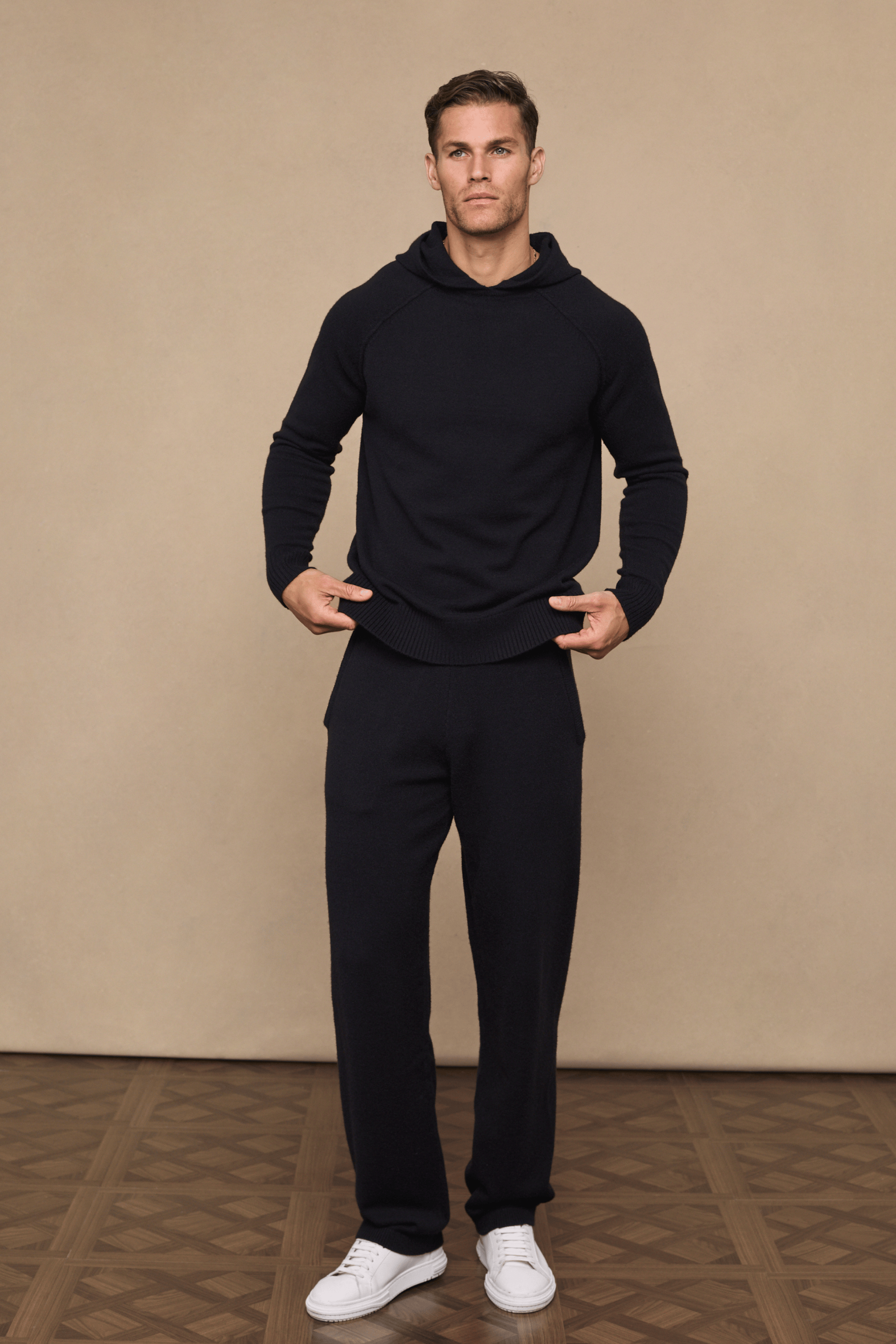 Man wearing a black Rowan Knitted Trouser and matching hoodie, posing with hands on the waistband.