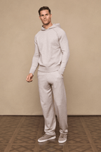 Man wearing a full Rowan Knitted Trouser and Hoodie set in oatmeal, with side pockets and drawcords.