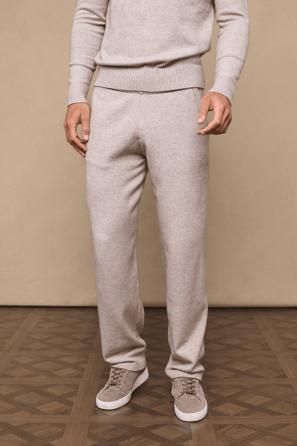 Model wearing oatmeal Rowan Knitted Trousers and matching sweater, showcasing soft fabric and side pockets.