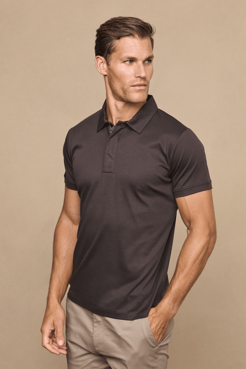 Man in a brown Santi mercerised cotton polo shirt with a concealed button placket and tan trousers.
