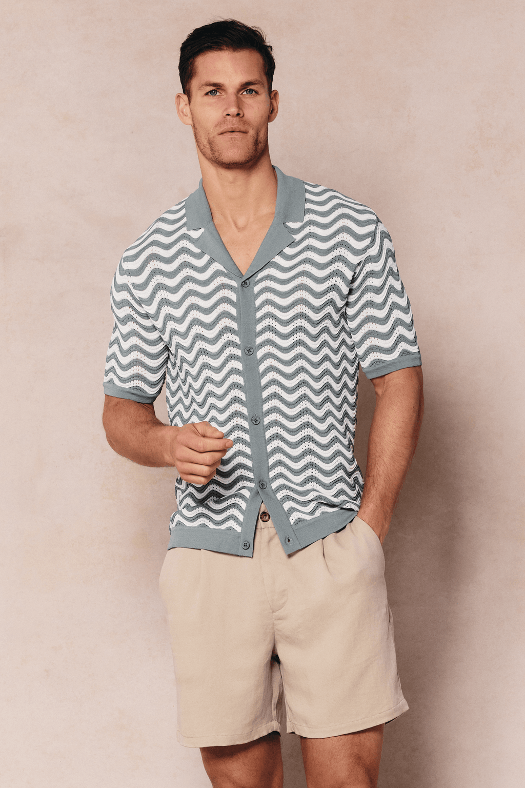 Man wearing a sage/white Serenita knitted shirt with a wave pattern, open collar, and button-through front.