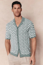 Man wearing a sage/white Serenita Knitted Shirt with a wave pattern, open collar, and button-through front.