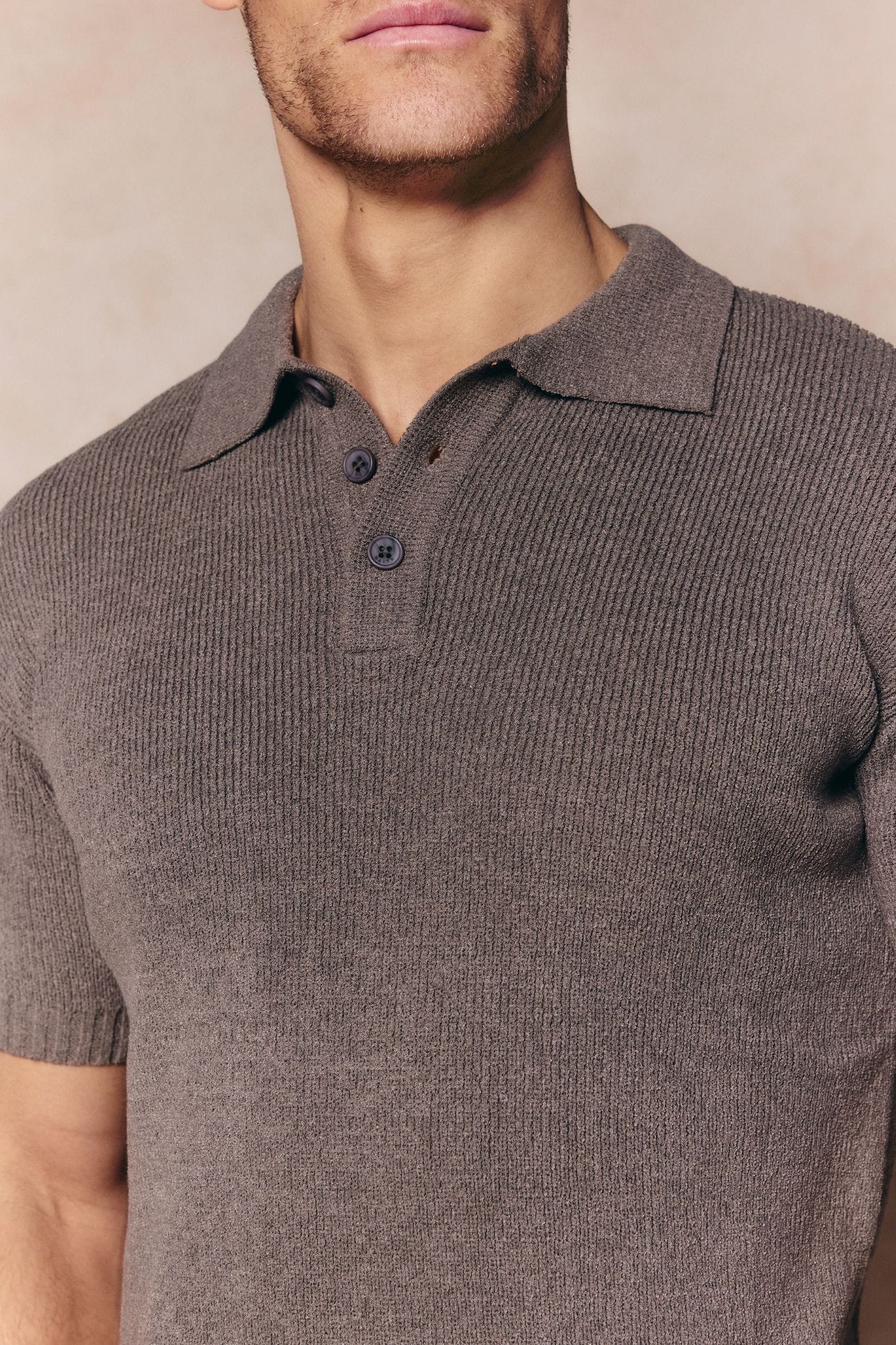 Man wearing a dark sage Sorelle short sleeve ribbed knit polo with a classic collar and button placket.