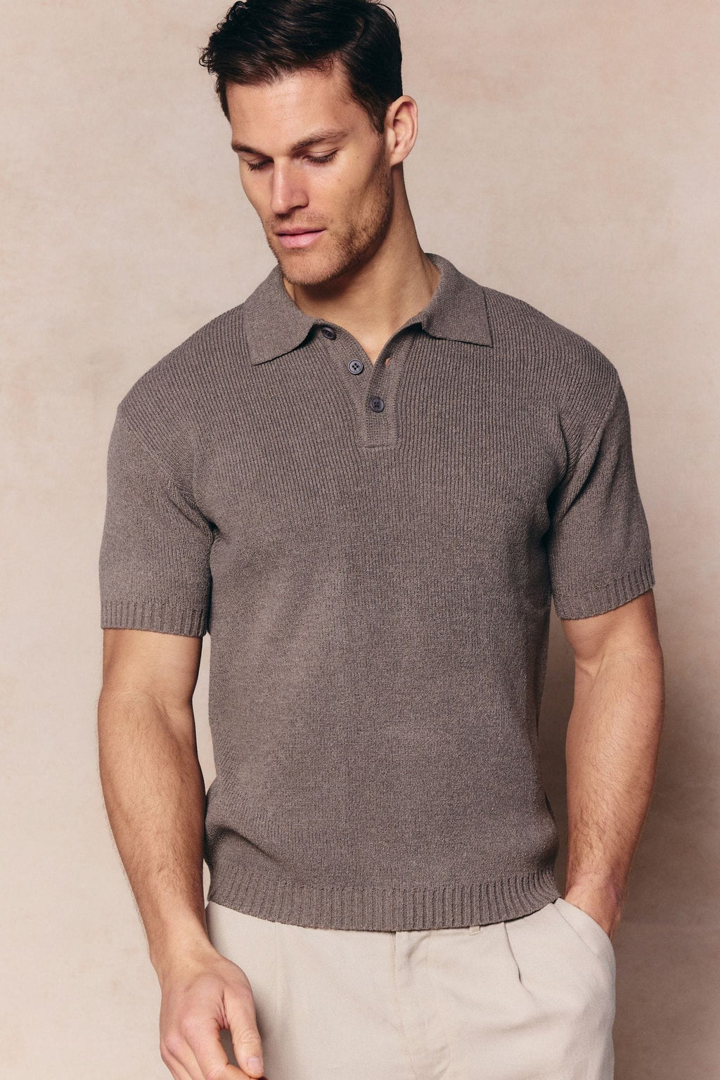Man wearing a dark sage Sorelle short sleeve ribbed knit polo with a classic collar and button placket.