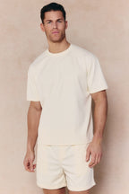 Man wearing an ecru Tomas Crew Neck Crinkled T-shirt with matching shorts.