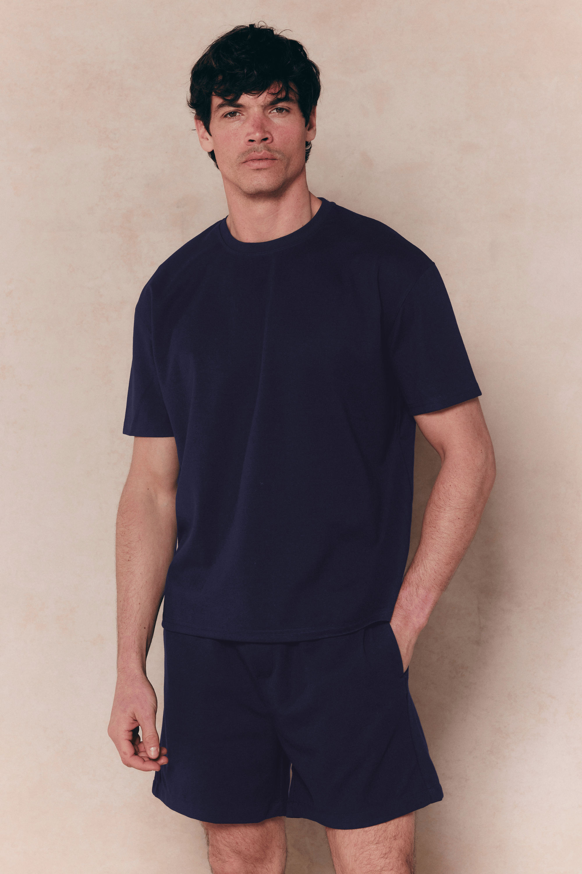 Man in a navy Tomas Crew Neck Crinkled T-shirt and matching shorts, relaxed fit.