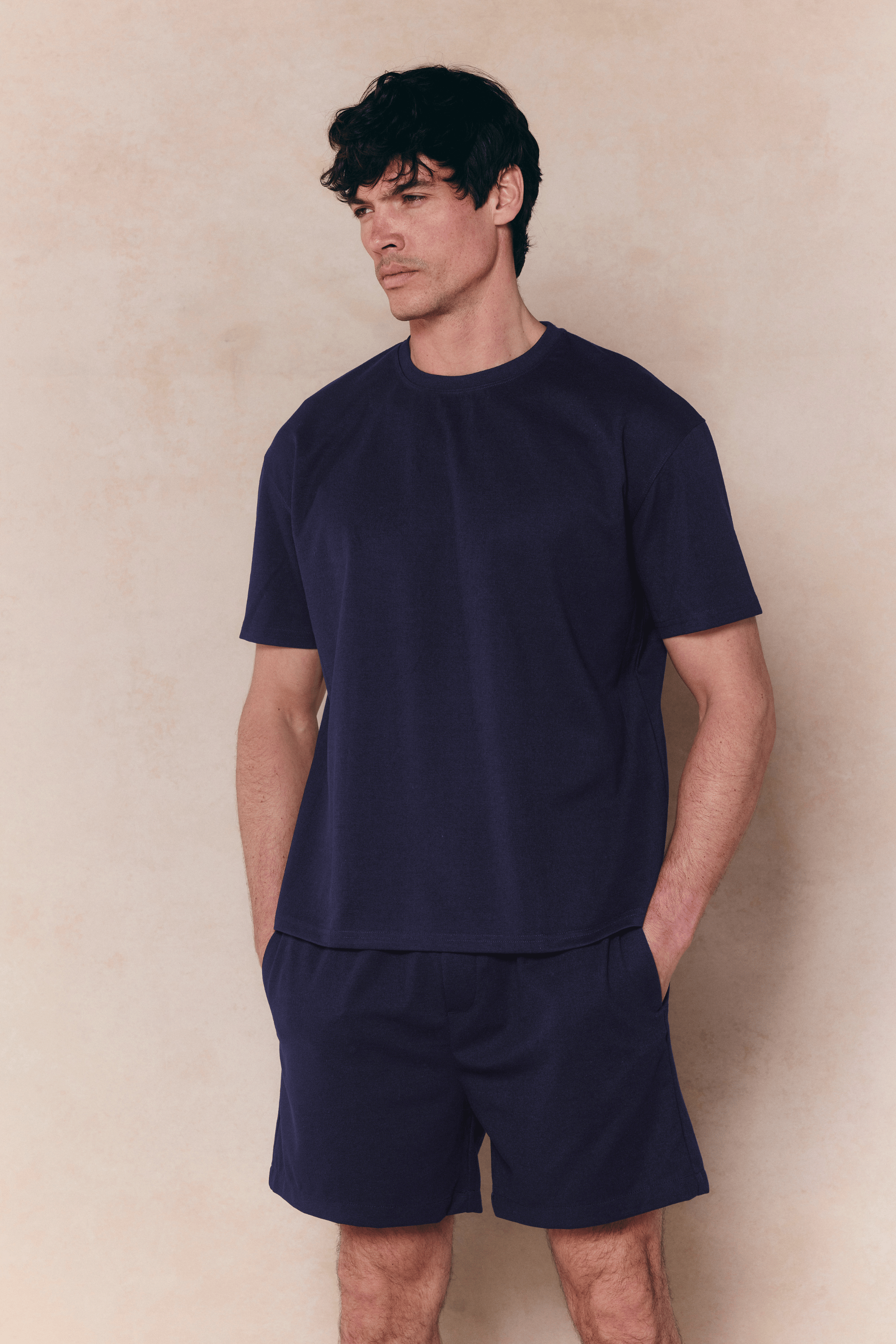 Man in a navy Tomas Crew Neck Crinkled T-Shirt and matching shorts, relaxed fit.