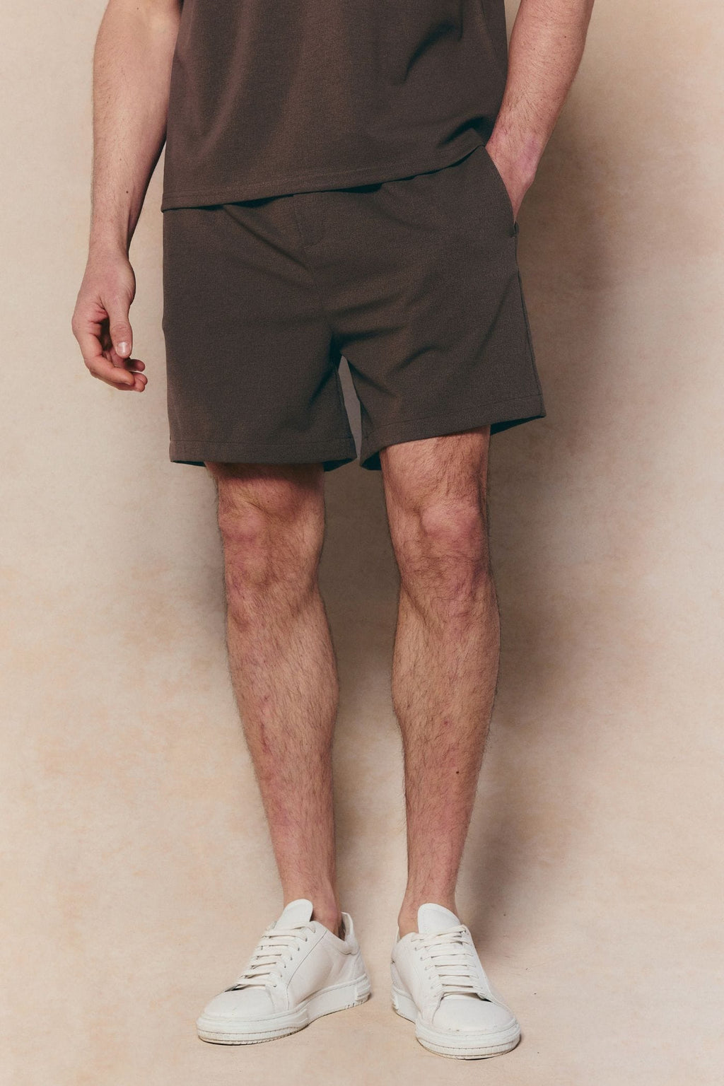 Dark brown Tomas elasticated waist shorts with crinkled texture, worn by a person in white sneakers.