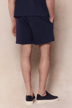 Man wearing navy Tomas Elasticated Waist Short with a subtle crinkled texture, relaxed fit, and elastic waistband.